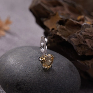 Macro shot of heart-cut yellow gemstone pendant with silver four-prong setting