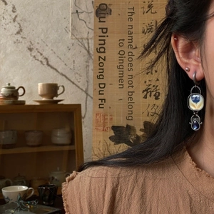 Close-up of vintage Egyptian style enamel earring with blue stone on female ear