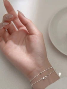 Close-up of minimalist double-layered silver heart bracelet worn on a female wrist