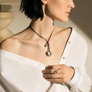 Irregular hollow metal pendant necklace and matching ring set worn by a female model
