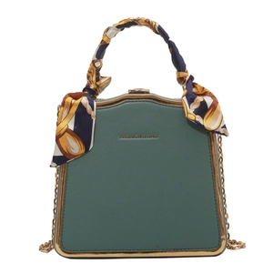 Elegant dark green trapezoid box bag with gold metal frame and silk scarf on handle