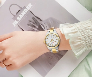 Detail of silver and gold quartz watch with waffle dial and date display on wrist