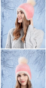 Close-up of pink knit winter hat featuring soft white faux fur trim and fluffy pom-pom