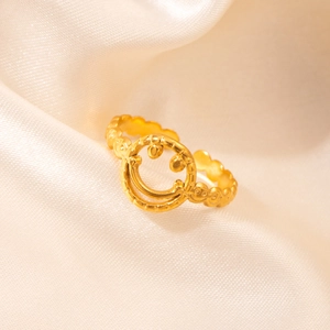 Macro shot of 18K gold plated smiling face ring on soft white satin background
