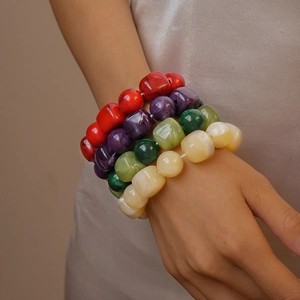 Close-up of four colorful acrylic bead bracelets on a female wrist in natural light