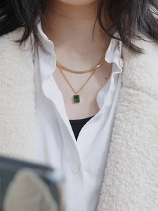 Close-up of double-layered gold snake chain featuring a rectangular emerald zircon pendant