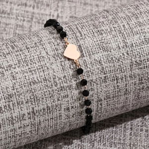 Detailed shot of beaded bracelet with black faceted beads and rose gold heart charm