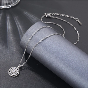 Macro shot of silver flower pendant with white cubic zirconia on a gray display pedestal