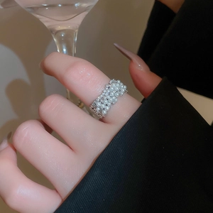 Detailed view of layered pearl ring on hand, featuring elegant gold plating and crystals