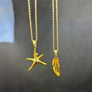 Detail of gold titanium steel necklaces featuring pearl starfish and feather pendants