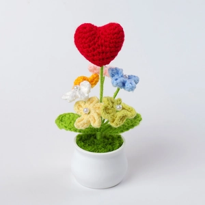 Macro detail of hand-knitted flower pot with a red heart and colorful crochet blooms