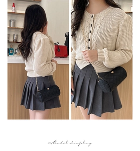 Model wearing a black cylinder crossbody bag with diamond quilting and gold hardware