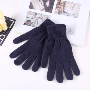 Flat lay of warm navy blue knitted winter gloves on a decorative background texture