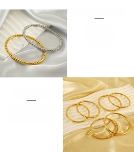 Detail of beaded stainless steel open bracelets in gold and silver on white silk