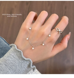 Dettaglio del bracciale di perle in argento S925 e anello con fiocco sulla mano