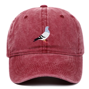 Detailed close-up of pigeon embroidery on washed red cotton vintage baseball cap
