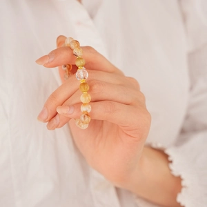 Close-up of Citrine beaded bracelet with faceted crystal centerpiece on white fabric