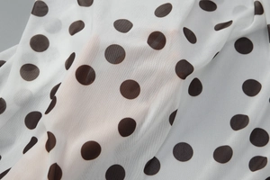 Gros plan sur un tissu léger à pois montrant la texture et la transparence