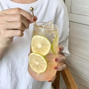Vertical ribbed glass cup with lemon slices, ice cubes and a metal stirring rod