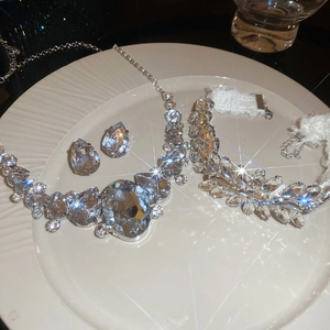 Detailed view of silver crystal waterdrop necklace earring bracelet set on ceramic plate