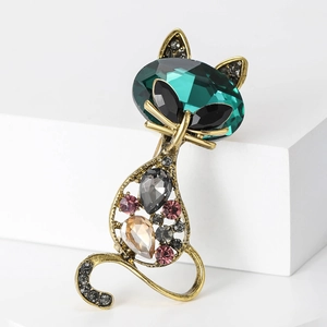 Detailed macro view of vintage gold cat brooch featuring emerald-green gemstone and crystals
