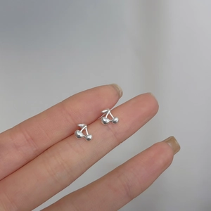 Detailed shot of small 925 silver cherry stud earrings held between fingers for size