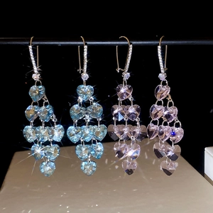 Detail of elegant heart-shaped crystal tassel earrings in light blue and purple colors