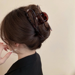 Close-up of a large amber leopard print hair claw clip securing a bun on long dark hair