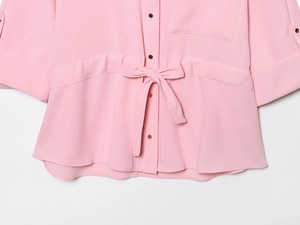 Détail d'un chemisier en mousseline rose à manches courtes avec nœud à la taille