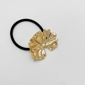 Close-up of golden ginkgo leaf metal charm on black high-elastic hair scrunchie