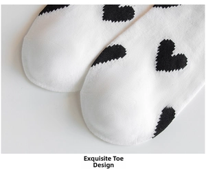 Detail of white cotton socks featuring black heart patterns and reinforced toe stitching