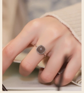 Close-up of a silver ring with a square grey jade stone on a model's finger