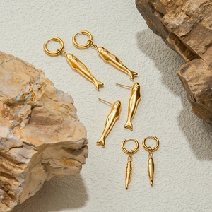 Modern minimalist 18k gold stainless steel hammered fish earrings on natural rocks