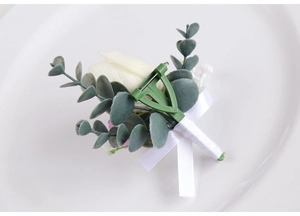 Detail view of the back of white silk rose boutonniere with green clip and safety pin