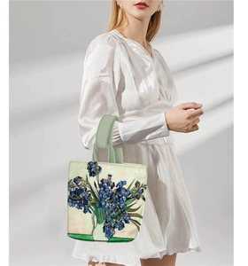 Detail of iris painting handbag with green handles against a minimalist wall