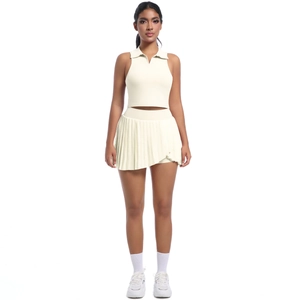 Détail de la jupe plissée crème et du crop top à revers pour le tennis et le fitness