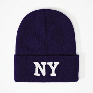 Close-up of white NY embroidery on dark purple knit beanie with ribbed texture