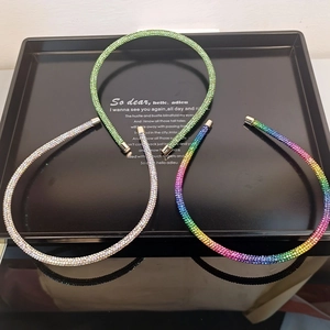 Close-up of thin sparkling rhinestone headbands in green, silver, and gradient colors