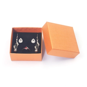 Close-up of orange jewelry gift box featuring elegant rhinestone earrings and ring set