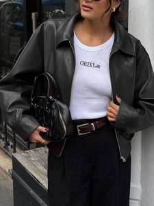 Close-up of black leather jacket with printed t-shirt and handbag in urban street style