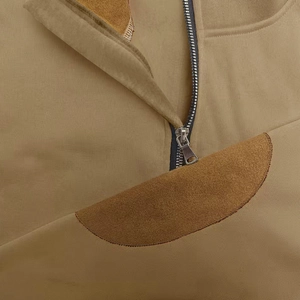 Close-up of metal zipper and brown suede patchwork on khaki outdoor stand collar sweatshirt