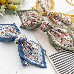 Flat lay detail of three floral satin hair scarves in blue pink and beige tones