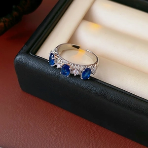 Gros plan d'une bague en argent ciselé avec pierres bleues et détails ajourés