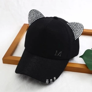 Detail of black baseball cap with rhinestone cat ears, metal rings and M logo