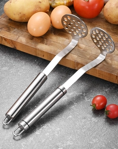 Détail macro de deux presse-purée en acier inoxydable avec boucles de suspension en cuisine