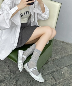 Detailed view of grey ribbed mesh socks paired with white ballet style flat shoes