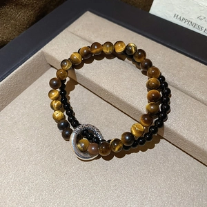 Detailed close-up of double-layer tiger eye and black bead bracelet with silver ornament