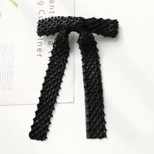 Detail of elegant black mesh bow hair clip with hand-stitched black beadwork and grid pattern