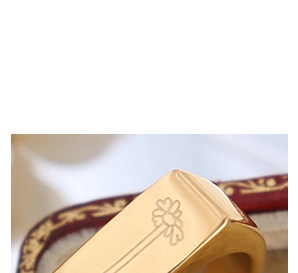 Close-up of a gold signet ring with engraved daisy pattern in a vintage velvet box