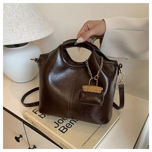 Detail view of vintage dark brown faux leather tote bag with gold chain and strap